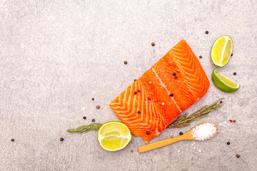 Raw trout (salmon) fillet piece with lime, rosemary, sea salt and pepper mix. Fish on a stone background, top view.