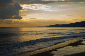 Sunset on the sea. Sandy beach. Twilight. Night lights.