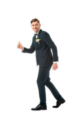 cheerful bridegroom in black suit showing thumb up isolated on white