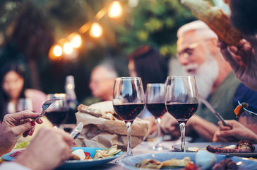 Happy family eating and drinking red wine at dinner barbecue party outdoor - Mature and young...