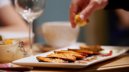 Cooked mussels served on a plate. A man squeezes lemon juice on top of it