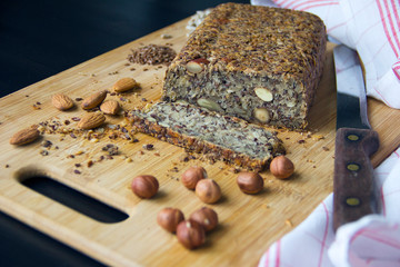 Fresh homemade keto bread with almonds, hazelnuts, sunflower seeds, chia seeds on a wooden cutting board