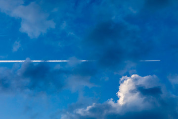 Plane flying through clouds with trail