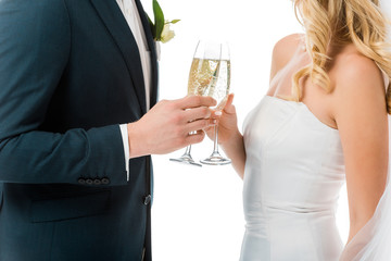 cropped view of bride and groom clinking glasses of champagne isolated on white