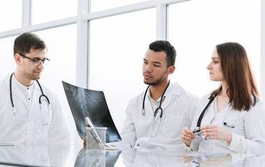 medical colleagues discuss x-ray, sitting at the office table