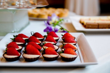 details of wedding treats with white cream and strawberries in chocolate cups