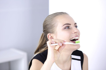 Smiling young woman with healthy teeth brushing her teeth