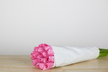 Big bouquet of pink tulips on a wooden table