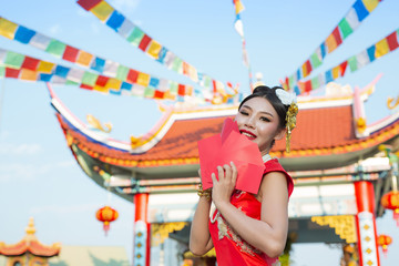 A beautiful asian girl wearing a red dress holding paper fan in her hand and smiling makes her look happy.