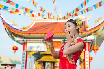 A beautiful asian girl wearing a red dress holding paper fan in her hand and smiling makes her look happy.