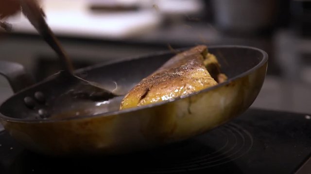 Chef cooking foie gras in a pan basting the foie gras