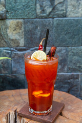 Iced tea with lemon slices and dried chilli  on glass of cup on wood background