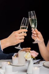 cropped view of man and woman holding glasses of champagne isolated on black