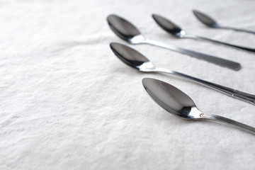 Vintage weathered silver metal spoon in pattern form on white fabric table top background with empty copy space for text