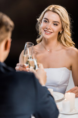 selective focus of young couple clinking glasses of champagne on black background