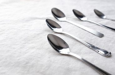 Vintage weathered silver metal spoon in pattern form on white fabric table top background with empty copy space for text