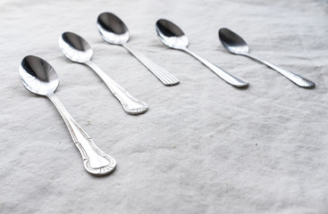Vintage weathered silver metal spoon in pattern form on white fabric table top background with empty copy space for text