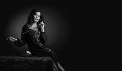  Portrait of attractive brunette  in negligee with old phone.