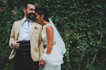 happy bride and groom in front of green wall