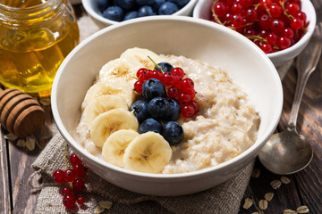 homemade oatmeal with berries on wooden background, closeup