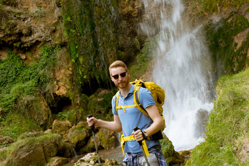 Obraz premium Young hiker stopped beside a mountain waterfall to rest