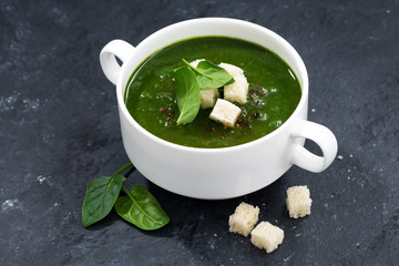 spinach cream soup with croutons on a dark background, closeup