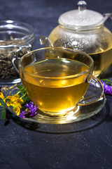 tea with aromatic herbs on a dark table, vertical