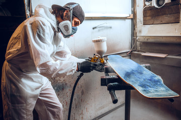 Master painter in a factory - industrial painting wood with spray gun.