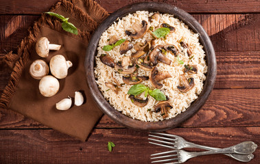 Cooked white rice with mushroomsin a bowl on wooden background.