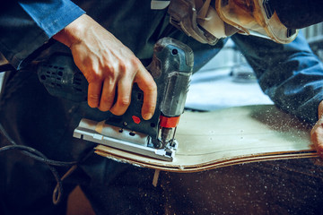 Carpenter using circular saw for cutting wooden boards. Construction details of male worker or handy man with power tools