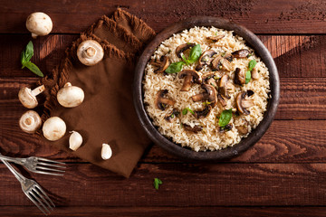 Cooked white rice with mushroomsin a bowl on wooden background.
