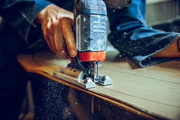 Carpenter using circular saw for cutting wooden boards. Construction details of male worker or...