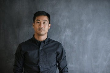 Confident Asian businessman standing in front of a blank chalkboard