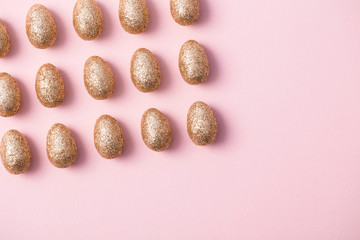 Gold glitter easter eggs on a pastel pink background. Happy Easter