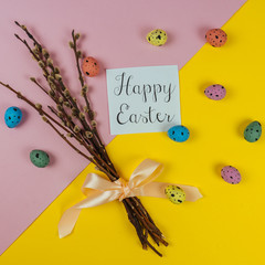 Happy Ester greeting card, willow brunches and painted quail eggs isolated on yellow and pink...