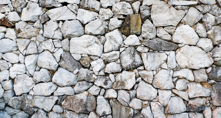 Rock stone wall background, pattern white-gray color design decorative cracked real stone wall surface.