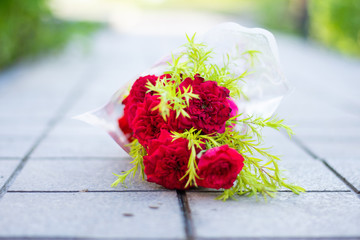 red rose flower bouquet delighted with the green leaves on the pavement