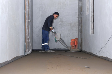 the workers grind the concrete floor at the construction site