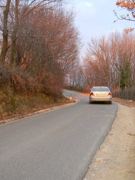 A car taking a left turn on a countryside road surrounded by trees