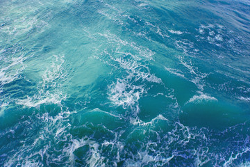 bright blue surface of ocean water with white foam, background, texture