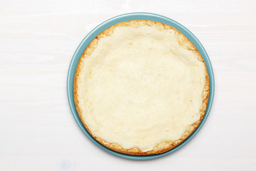 Whole cheesecake on a wooden white table. Top view.