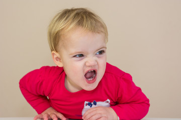 Cute blonde girl wearing red dress making evil faces.