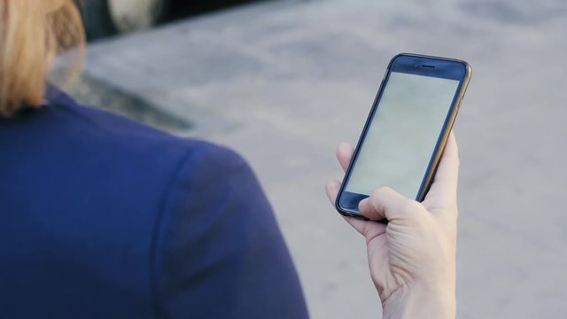 Chica sostiene m&oacute;vil en la calle (para reemplazar pantalla).