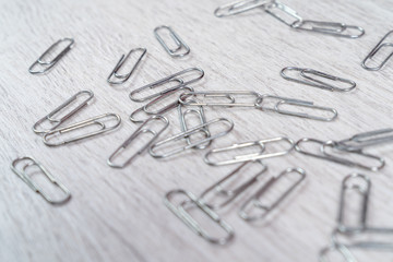Fototapeta premium Paper clips scattered on a gray wooden surface