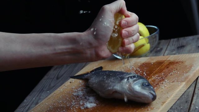 A chef squeezes a half cut lemon over fish and chips