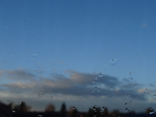 Wolken und Himmel durch das Fenster mit Regentropfen fotografiert