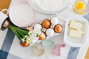 Baking ingredients placed on wooden table, ready for cooking. Concept of food preparation, white kitchen on background.