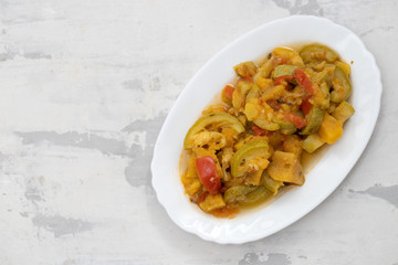 vegetable stew in white dish on ceramic background