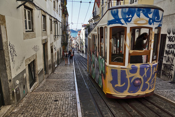 Plakat alte mit Graffiti bemalte Straßenbahn in Lissabon fährt Berg hoch, Portugal 