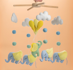 Colorful and eco-friendly children's mobile from felt for children. On light brown background.